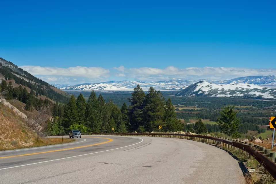 Curve in mountain highway along Teton Pass with snowy Wyoming mountains in background.